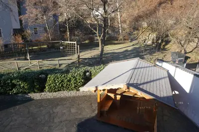 a wooden bench with a roof on a sidewalk at Hotel & Residence Sylvanerhof in Chiusa