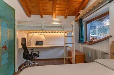 a bedroom with a bunk bed and a desk and a chair at Chalet Kalipe in Rocca Pietore