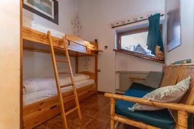 a bunk bed room with two bunk beds and a chair at Chalet Kalipe in Rocca Pietore