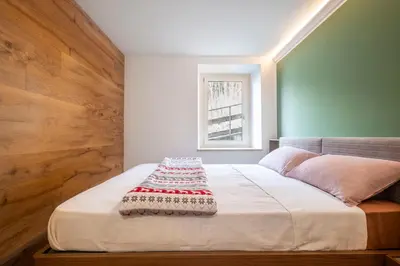 a bedroom with a bed with a blanket on it at GuestHost - Dolomite Elegance - Chic Flat in San Vito di Cadore in Termine