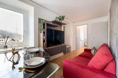 a living room with a red couch and a table at GuestHost - Dolomite Elegance - Chic Flat in San Vito di Cadore in Termine
