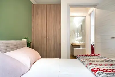 a bedroom with a white bed and a bathroom at GuestHost - Dolomite Elegance - Chic Flat in San Vito di Cadore in Termine