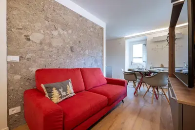 a living room with a red couch and a table at GuestHost - Dolomite Elegance - Chic Flat in San Vito di Cadore in Termine