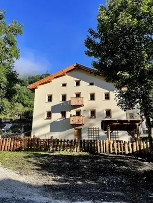 a large white building with a fence in front of it at Casa Alice in Rocca Pietore