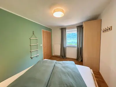 a bedroom with a bed with a green wall at Haslingerhof - Ferienwohnung Hirzer in Saltusio