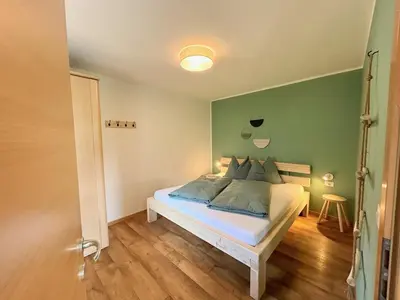 a bedroom with a bed with a green wall at Haslingerhof - Ferienwohnung Hirzer in Saltusio