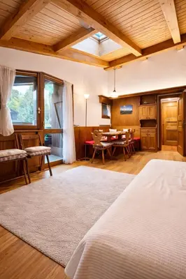 a bedroom with a bed and a dining room at Cà Masariè Alverà in Cortina dʼAmpezzo