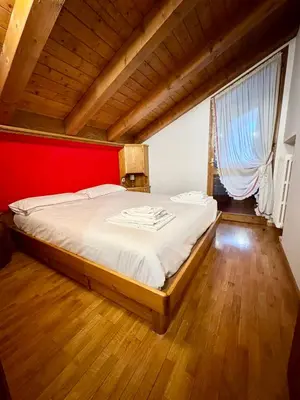 a bedroom with a large bed with a red wall at Cà Masariè Alverà in Cortina dʼAmpezzo