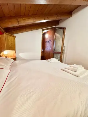 a white bed with two towels on top of it at Cà Masariè Alverà in Cortina dʼAmpezzo