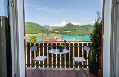 a balcony with a table and chairs and a view of the water at Am See Apartments in Castelvecchio