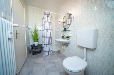 a white bathroom with a toilet and a sink at Am See Apartments in Castelvecchio