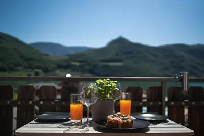 a table with a plate of food and glasses of orange juice at Am See Apartments in Castelvecchio