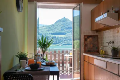 a kitchen with a table with a view of a balcony at Am See Apartments in Castelvecchio