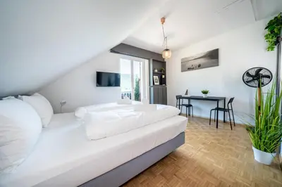 a white bedroom with a bed and a table at Am See Apartments in Castelvecchio