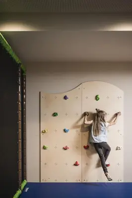 a young girl is climbing a climbing wall at Falkensteiner Hotel Falkensteinerhof l 4 Star Superior in Valles