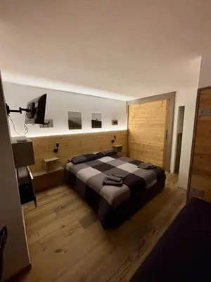 a bedroom with a large bed and a flat screen tv at Pragma Apartments - Fiore delle Alpi in Bellamonte
