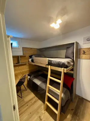 a room with two bunk beds and a stool at Pragma Apartments - Fiore delle Alpi in Bellamonte