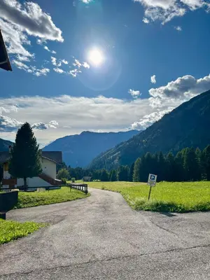 a road leading into a field with mountains in the background at Pragma Apartments - Fiore delle Alpi in Bellamonte