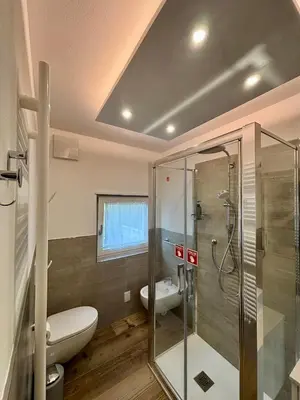 a bathroom with a toilet and a glass shower at Pragma Apartments - Fiore delle Alpi in Bellamonte