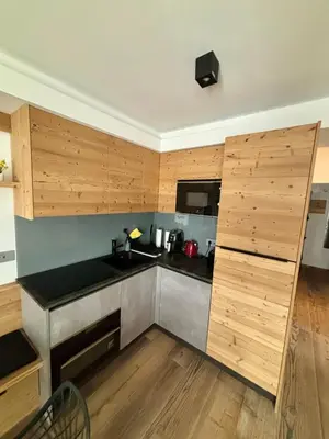 a kitchen with wooden cabinets and a black counter top at Pragma Apartments - Fiore delle Alpi in Bellamonte