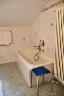 a white bath tub with a blue stool in a bathroom at Oberortsgut in Tirolo
