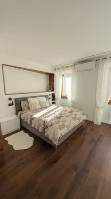 a bedroom with a bed and wooden floors and windows at Appartamento Alpino Cles in Cles