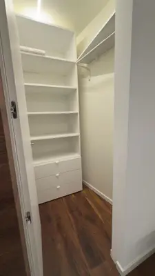 a walk in closet with white shelves and wood floors at Appartamento Alpino Cles in Cles