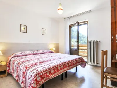 a bedroom with a large bed and a window at Apartment El Ladinia-2 by Interhome in Moena