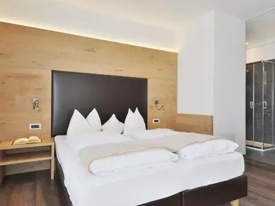 a bedroom with a large white bed with a black headboard at Holiday Home Kostner-2 by Interhome in Bulla