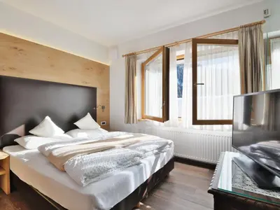 a bedroom with a large bed and a television at Holiday Home Kostner-2 by Interhome in Bulla