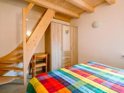 a colorful bed in a room with a staircase at Apartment Saslench by Interhome in Pera