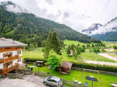 a green house with wooden balconies and a fence at Apartment Saslench by Interhome in Pera