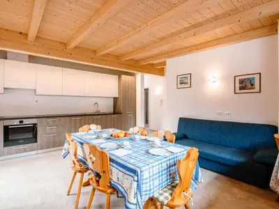 a dining room with a table and a blue couch at Apartment Saslench by Interhome in Pera