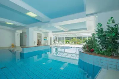 a large swimming pool with blue tile floors and a swimming pool at Hotel Mühle Mayer in Termeno