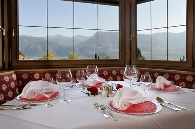 a table with red and white plates and wine glasses at Hotel Mühle Mayer in Termeno