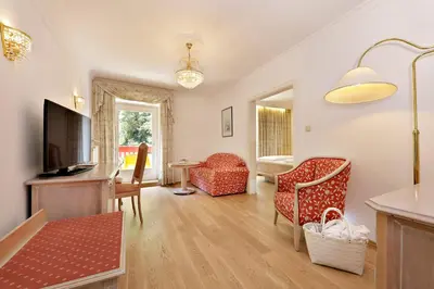 a living room with a flat screen tv and chairs at Hotel Mühle Mayer in Termeno