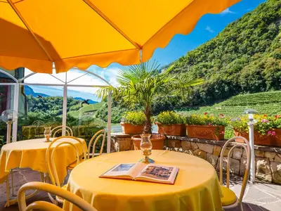 two tables with yellow table umbrellas on a patio at Hotel Mühle Mayer in Termeno