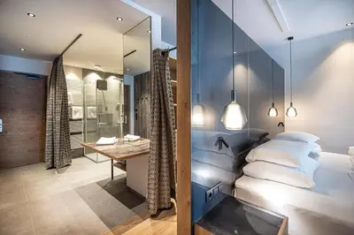a bedroom with a bed and a desk and a mirror at Vitalpina Hotel Waldhof in Rablà
