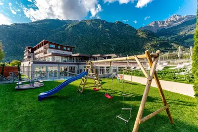 a playground with a slide and a swing at Vitalpina Hotel Waldhof in Rablà