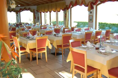 a restaurant with white tables and chairs and windows at Gardenhotel Premstaller in Bolzano