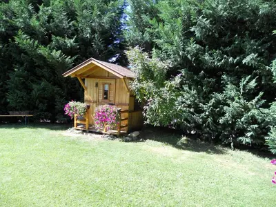 a small wooden house with flowers in a yard at Gardenhotel Premstaller in Bolzano
