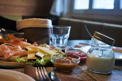 a table with a plate of food with cheese and other foods at Guesthouse Dolomiten in Egna