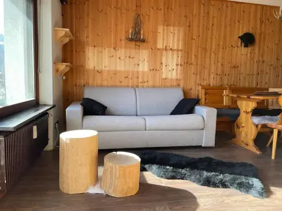 a living room with a couch and two wooden stools at CIASA LAURINA - Apartment near the slopes with Dolomite views in Carezza al Lago