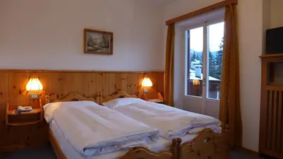 a bedroom with two beds and a window at Hotel Bellaria - Cortina d'Ampezzo in Cortina dʼAmpezzo