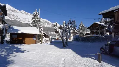 a snow covered street with a building and a snow covered mountain at Hotel Bellaria - Cortina d'Ampezzo in Cortina dʼAmpezzo