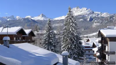 a snow covered city with snow covered trees and mountains at Hotel Bellaria - Cortina d'Ampezzo in Cortina dʼAmpezzo
