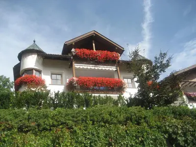 a white building with red flowers in the windows at Apartment Manuel in Ortisei