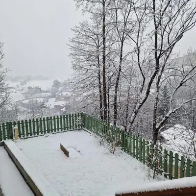 a fence covered in snow with trees in the background at Appartamento Genzianella Monolocale in Cavalese