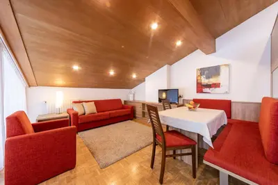 a living room with a table and red chairs at Waldelerhof- Appartements in Meransen in Maranza