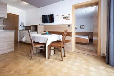 a dining room with a table and chairs and a bedroom at Waldelerhof- Appartements in Meransen in Maranza